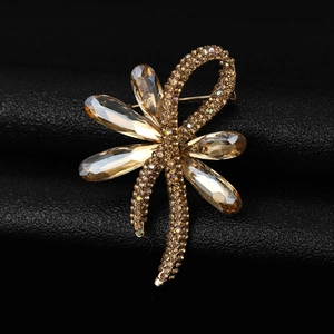 Macro shot of gold-plated ribbon brooch with champagne teardrop crystals and pavé rhinestones