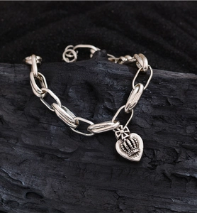 Close-up of vintage 925 silver heart crown pendant on a retro link chain bracelet