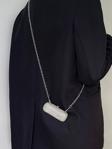 Close-up of silver rhinestone lipstick mini crossbody bag with chain on black blazer