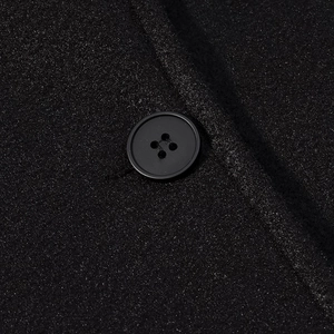Macro shot of black textured tweed fabric detail with a classic four-hole button
