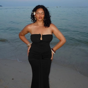Detail of elegant black strapless mermaid dress with slim fit on beach at sunset