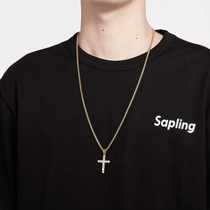 Close-up of a gold hip hop cross pendant with micro-paved zircons worn by a male model