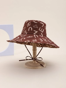 Detail of a brown wide-brim sun hat featuring white heart and letter graffiti patterns