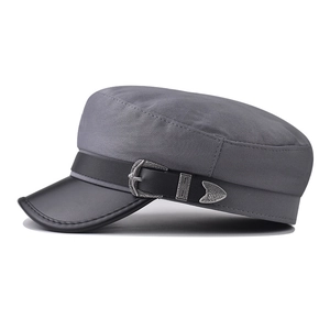 Close-up of grey suede military hat with black leather brim and ornate silver buckle detail