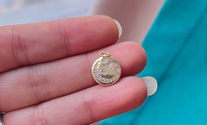 Macro shot of a golden celestial charm pendant featuring star and moon motifs held by hand