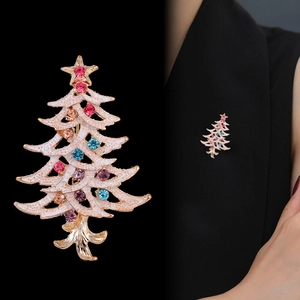 Golden Christmas tree brooch with colorful crystals and white enamel on black background