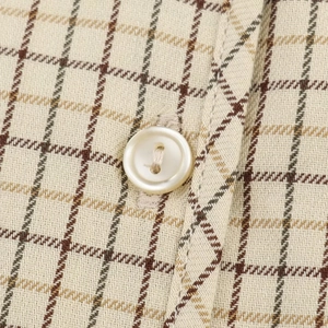 Close-up of beige plaid shirt with intricate weave texture and white button detail