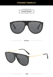Detail of oversized sunglasses with metallic rivets and sleek golden temple design