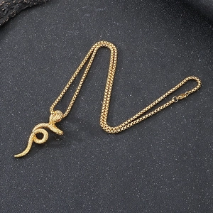 Gros plan du pendentif serpent plaqué or aux yeux rouges sur une chaîne à mailles