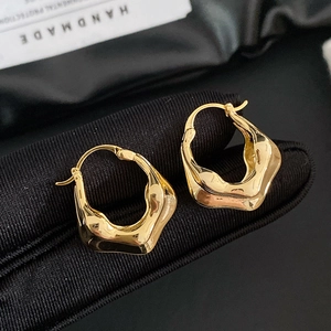 Boucles d'oreilles dorées évidées à vagues irrégulières sur tissu noir