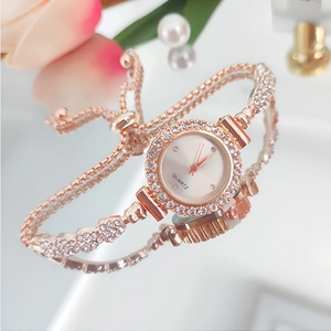 Detail of rose gold quartz watch with rhinestones on a mirror near pink roses