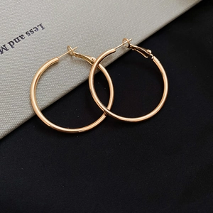 Detailed view of polished gold hoop earrings with secure click-top closure on textured leather