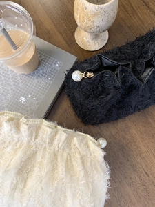 Détail de trousses à maquillage en peluche noir et crème avec fermetures en perles