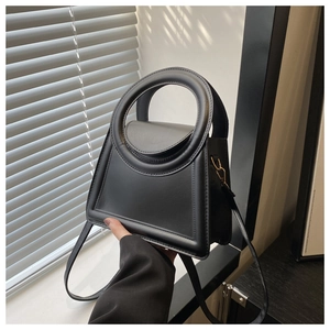 Detail of minimalist black leather crossbody bag with distinctive circular cutout handle