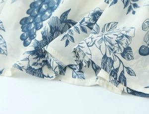 Close-up of square neck dress fabric showing blue floral prints and fine stitching