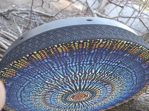 Close-up of handmade Shaman drum featuring a colorful mosaic mandala pattern and woven edge
