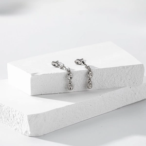 Detail shot of silver S925 asymmetric fluid tassel earrings on textured white stone