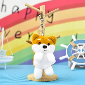 Κοντινό πλάνο χαριτωμένου καφέ και λευκού Shiba Inu λούτρινου μπρελόκ σε ξύλινη βάση έκθεσης