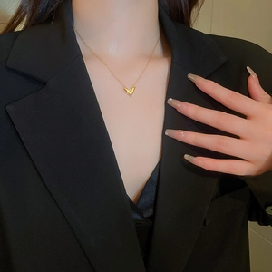 Gros plan d'un collier en V doré minimaliste sur un mannequin avec texture métallique