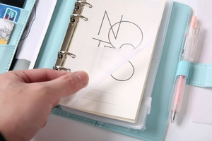 Detail of light blue leather binder showing multi-functional card slots and pen holder