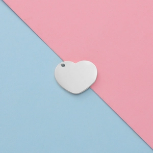 Polished silver stainless steel heart pendant for DIY jewelry on pink and blue background