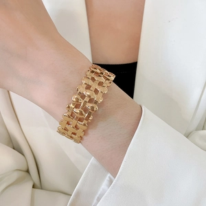 Detailed view of wide gold metal hollow-out bracelet with polished interlaced design