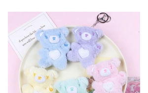 Close-up of colorful plush bear keychains with white hearts in a white decorative tray