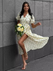 Detail of floral wrap dress with yellow tulip prints and puff sleeves on stone background