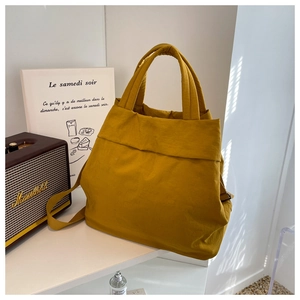 Detail of a ginger yellow nylon tote bag with pleated texture and adjustable strap