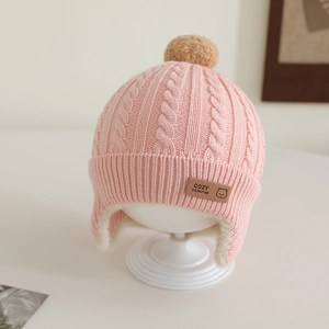 Close-up of pink baby winter hat with thick white fleece lining and soft pom-pom detail