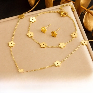 Detail of gold flower jewelry set featuring necklace and earrings on satin background