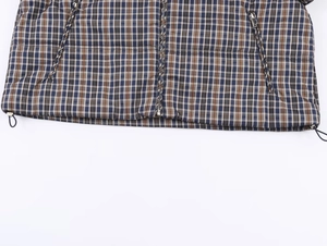 Detail of plaid jacket featuring metal zipper, zipped pockets and adjustable hem drawstring