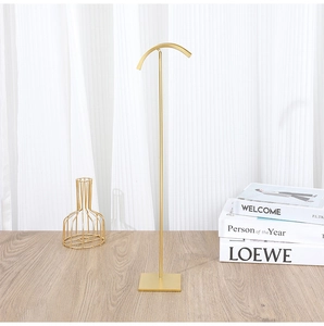 Detail of gold metal display stand with curved top bar for necklaces and handbags