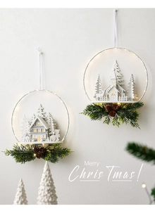 Detail of lighted white wood Christmas door hanger with pine needles and cones