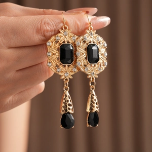 Detail of vintage gold drop earrings with black stones and intricate cutout design