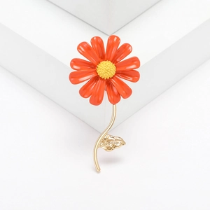 Minimalist orange daisy flower brooch with golden stem on a clean white background