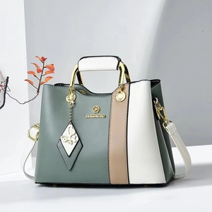 Elegant color-block tote bag with metal handles and butterfly charm in green and white