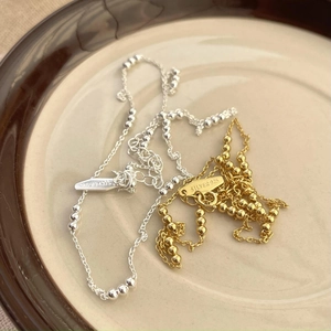 Detail of 925 sterling silver bead necklaces in gold and silver on a ceramic tray