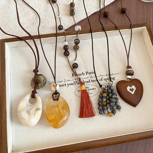 Close-up of Bohemian necklaces with resin stones and tassels in a wooden tray