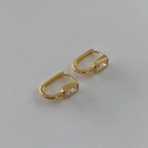 Macro view of gold U-shaped earring with rectangle cubic zirconia on white background
