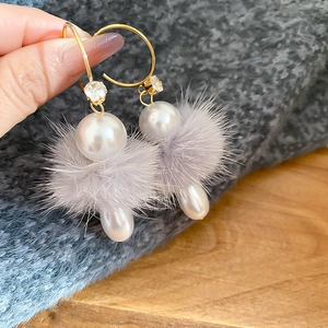 Détail de boucles d'oreilles avec perles blanches, pompons gris et accents de zircon