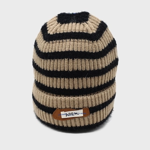 Close-up of thick ribbed knit fabric and ADER brand patch on striped winter beanie