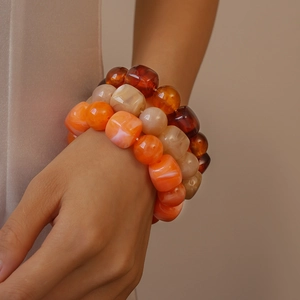 Detail of three-piece acrylic beaded bracelets with amber marble texture and square beads