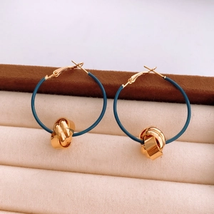 Close-up of blue twisted hoop earrings with gold knot detail on jewelry box