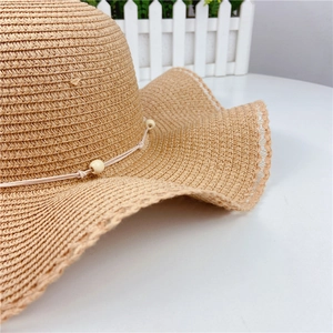 Close-up of a wide brim straw sun hat with delicate lace edging and beaded detail