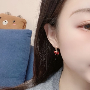 Close-up of a model wearing a golden butterfly earring with red zircon stones
