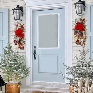 Christmas door swag with red bow, pine cones and warm LED lights on a blue door