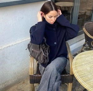 Manteau en laine bleu foncé à col montant pour femme avec jean large dans un café
