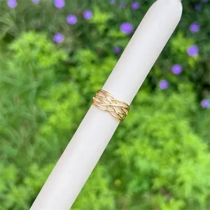 Makroaufnahme von vergoldetem geflochtenem Netzring mit Schichtdesign auf weißem Sockel