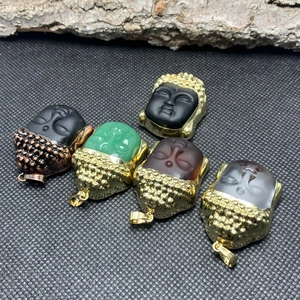 Detail view of five crystal Buddha head pendants with gold and bronze metal plating